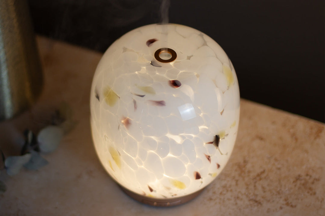White confetti glass aroma diffuser close up showing the mist and light on