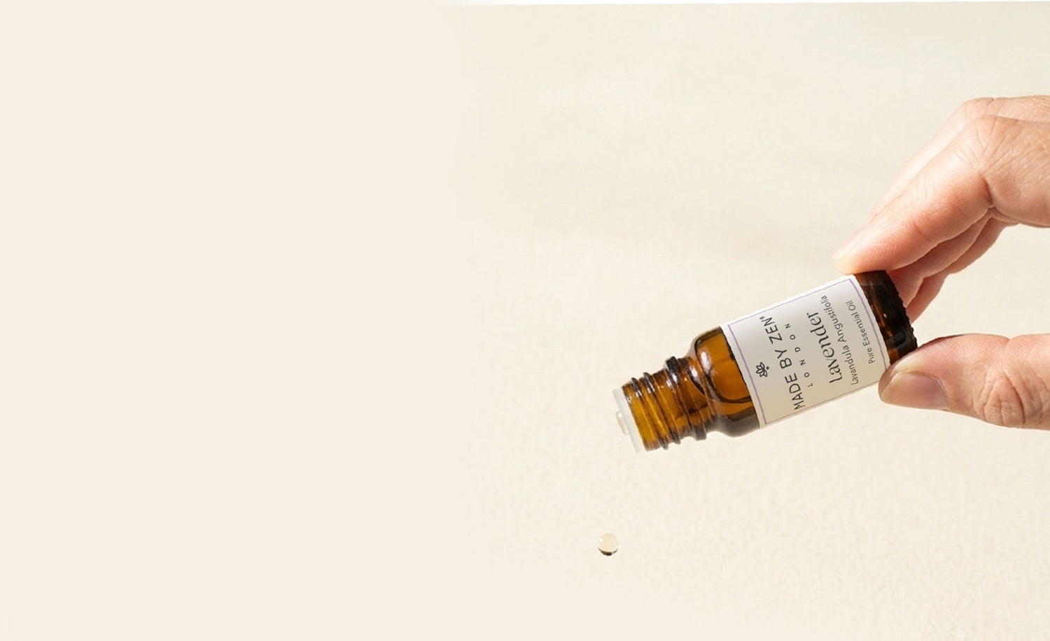 Lavender oil bottle in hand on an angle, oil dripping out of the bottle