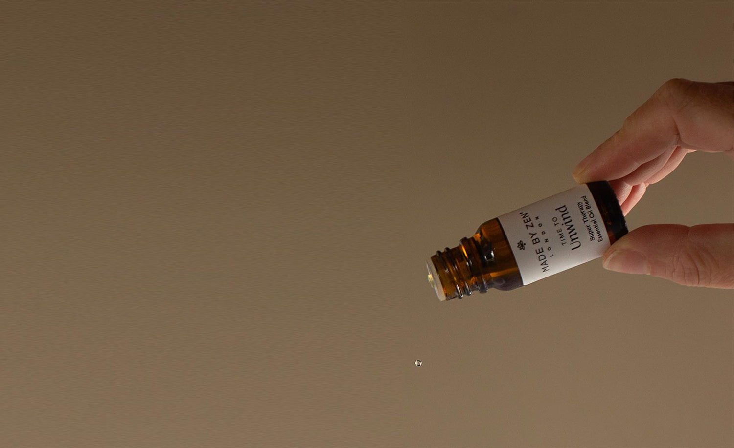 Oil bottle in hand on an angle, oil dripping out of the bottle