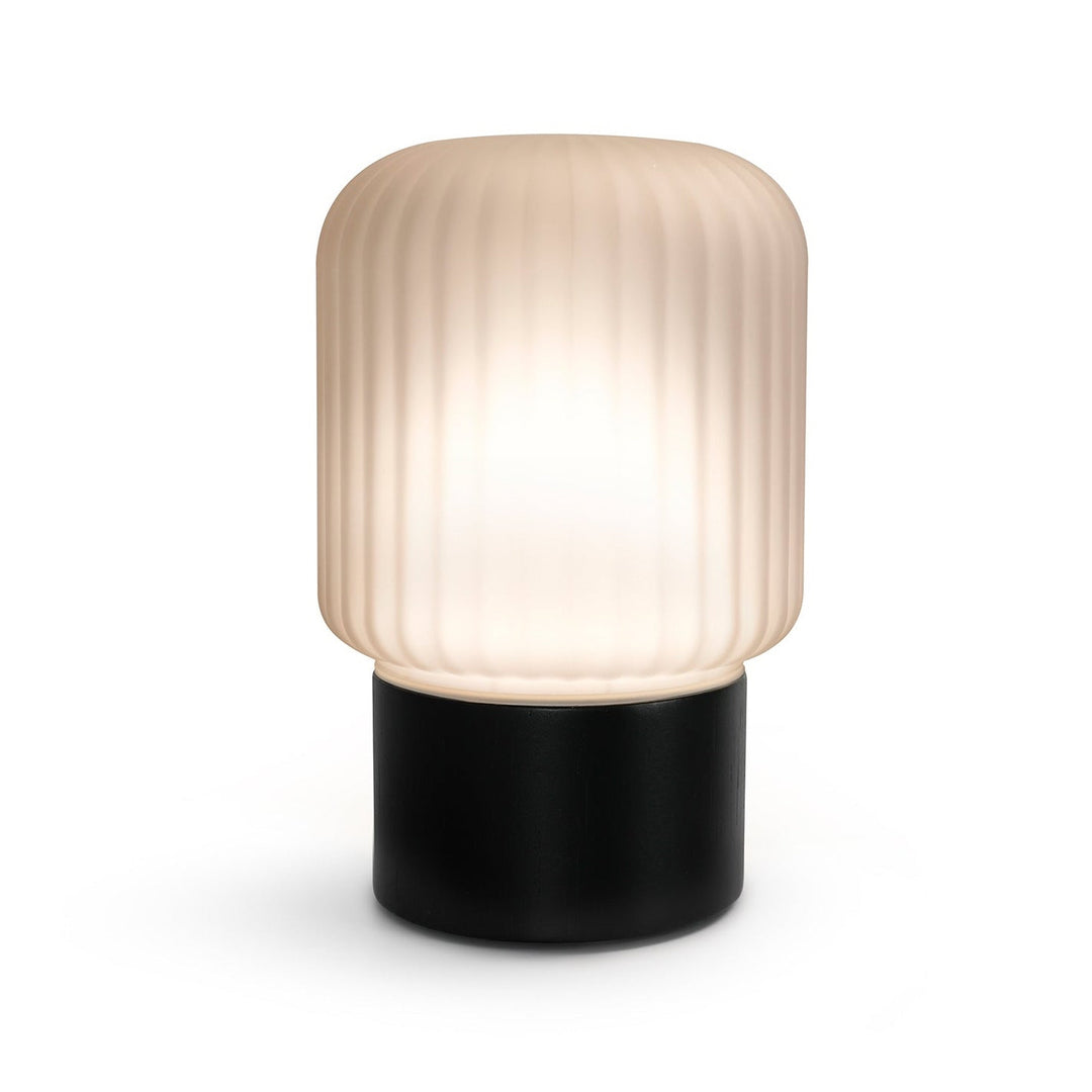 Made by Zen aroma diffuser with a ribbed, cylindrical frosted glass shade that glows warm white, mounted on a matte black cylindrical bamboo base, shown against a plain white background.