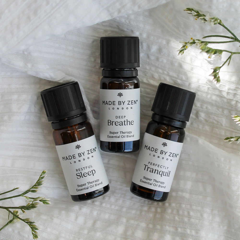 3 oil bottles lay on linen material with foliage