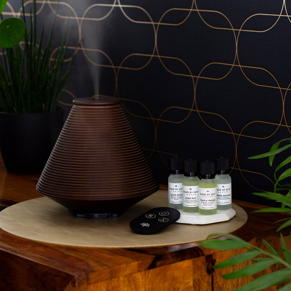 Wooden aroma diffuser with intricate groove design, offers a variety of mist settings. Supplied with remote control and four fragrance oils