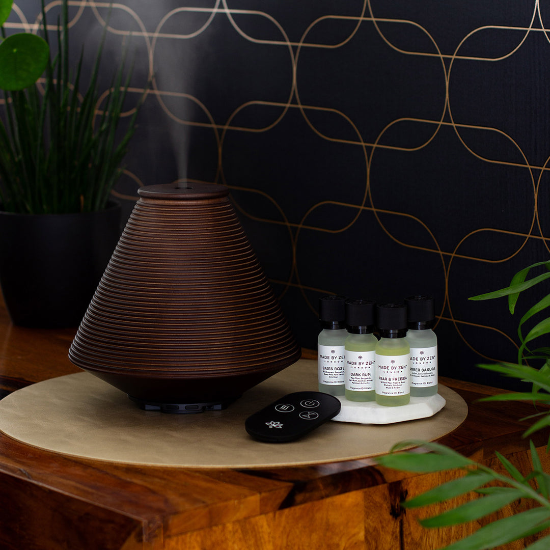 Wooden aroma diffuser with intricate groove design, offers a variety of mist settings. Supplied with remote control and four fragrance oils